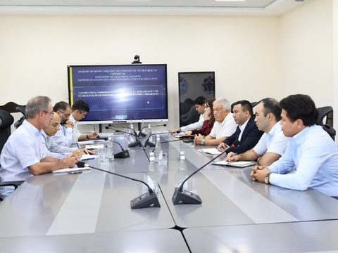 Французские и узбекские специалисты за столом переговоров, на экране презентация