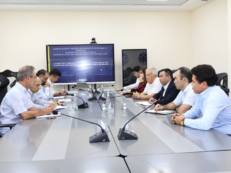 French and Uzbek specialists at a meeting table with a presentation screen
