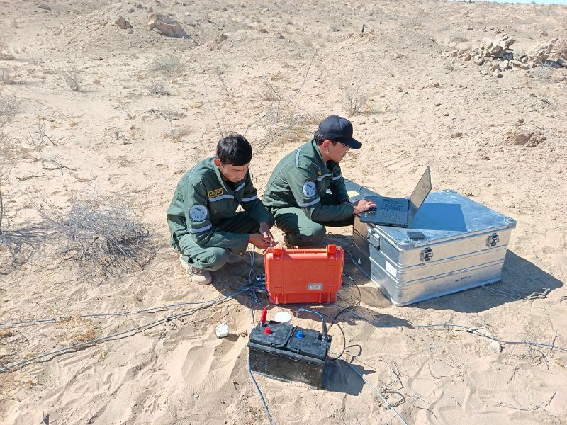Two geophysicists with field instruments in a sandy desert