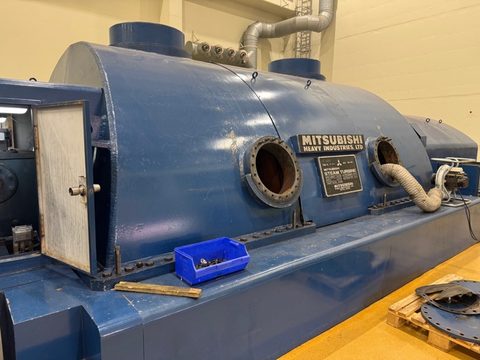 A large blue Mitsubishi steam turbine casing in a turbine hall