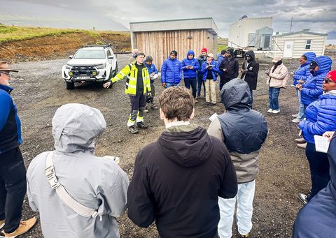 A Norðurorka engineer in a high-visibility jacket speaking to fellows outdoors at a production site