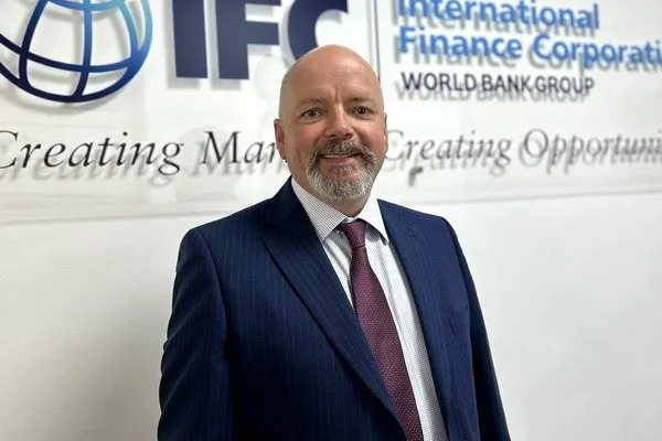 Нил Маккейн (IFC) на фоне баннера IFC