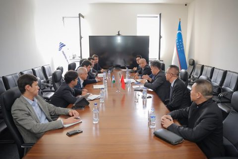 Uzbek and Chinese representatives at a meeting table with national flags
