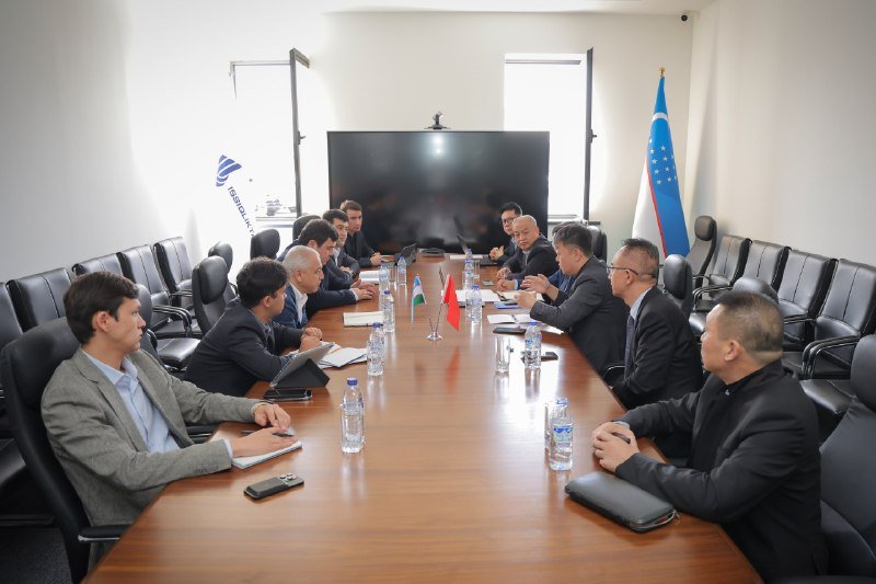 Uzbek and Chinese representatives at a meeting table with national flags