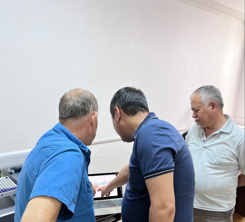Laboratoriyada noutbuk ekraniga qarab turgan uch kishi