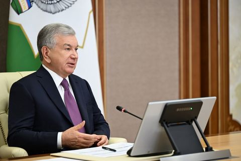 President Shavkat Mirziyoyev speaks at the meeting on greenhouses, seated at a desk with a microphone
