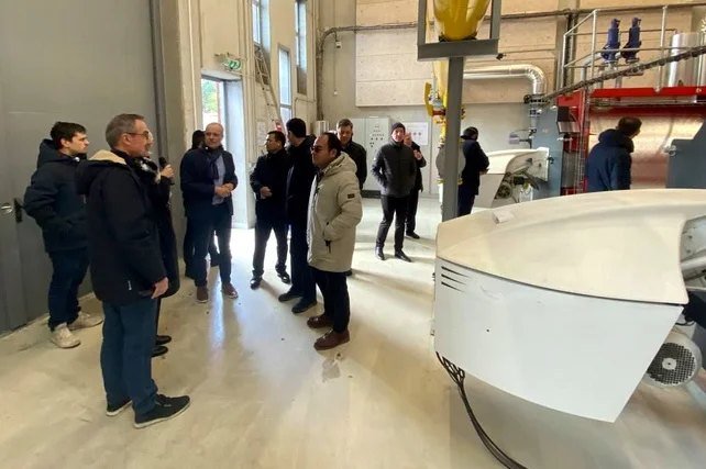 Members of the delegation inside a plant room with pumps and pipework