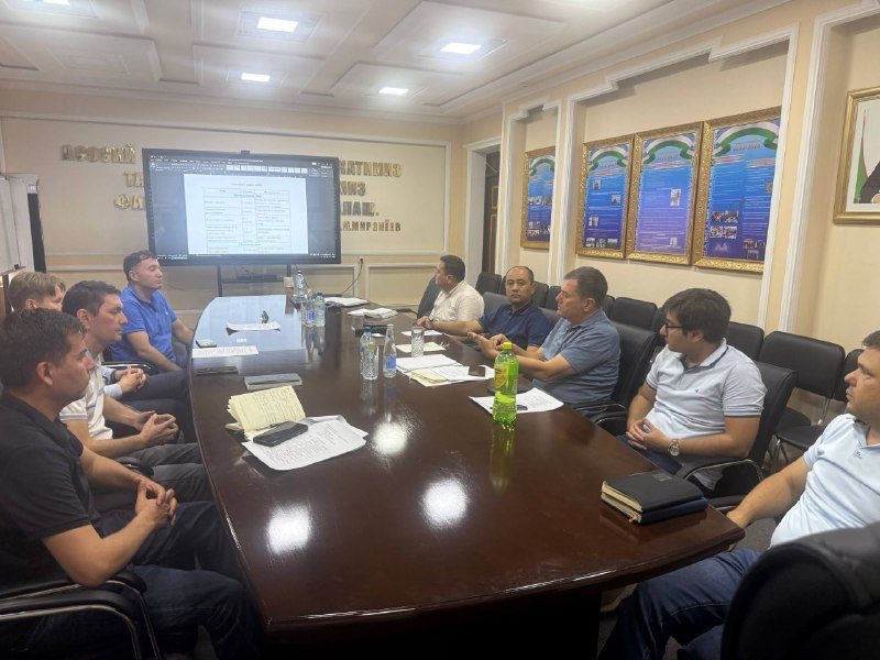 Specialists around a long meeting table, with a document on a large screen