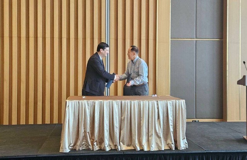 Two officials shaking hands after signing a memorandum